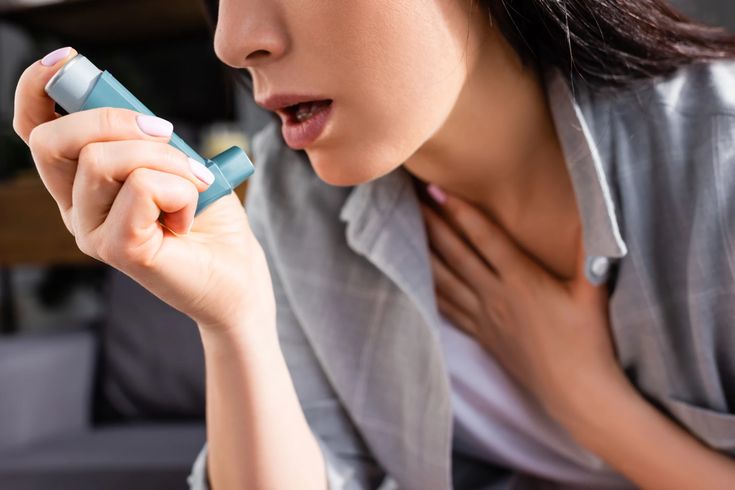 Woman reaching for her asthma inhaler while catching her breath