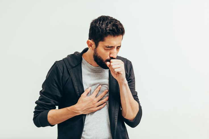 Man coughing with a hand held to his chest