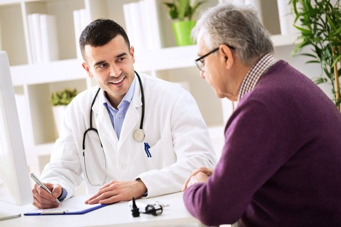 Doctor at a computer talking a patient through their treatment plan